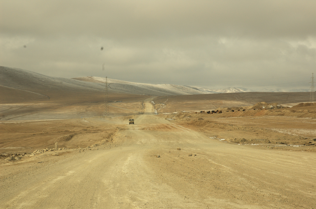 Dusty road in a desert landscape with a car