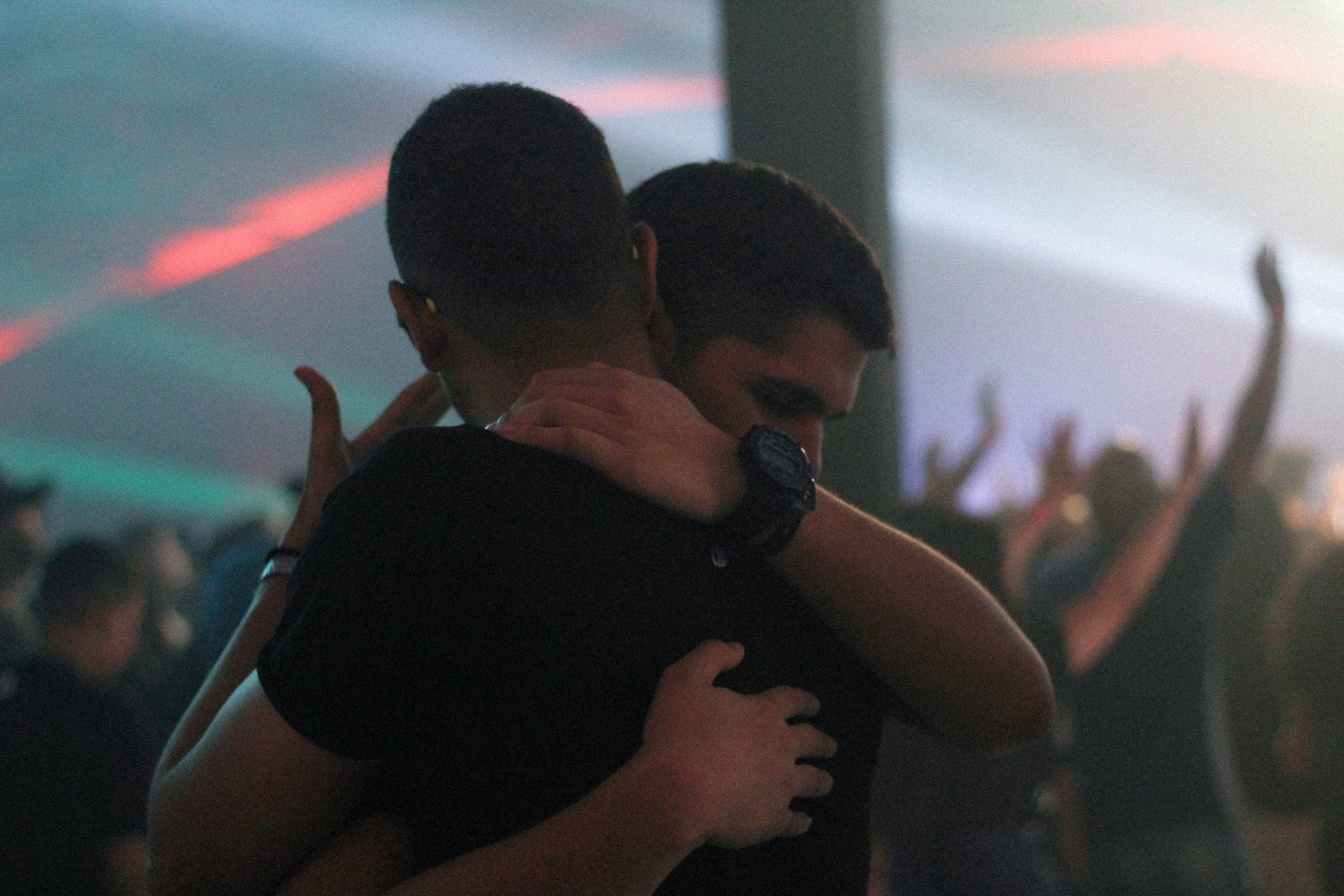 A picture of two people hugging at what looks like a disco. It is dark and lit with strobe lights.